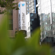 A sig for the exterior of Twitter's headquarters on the side of a large brick building with grass blurred in the foreground.